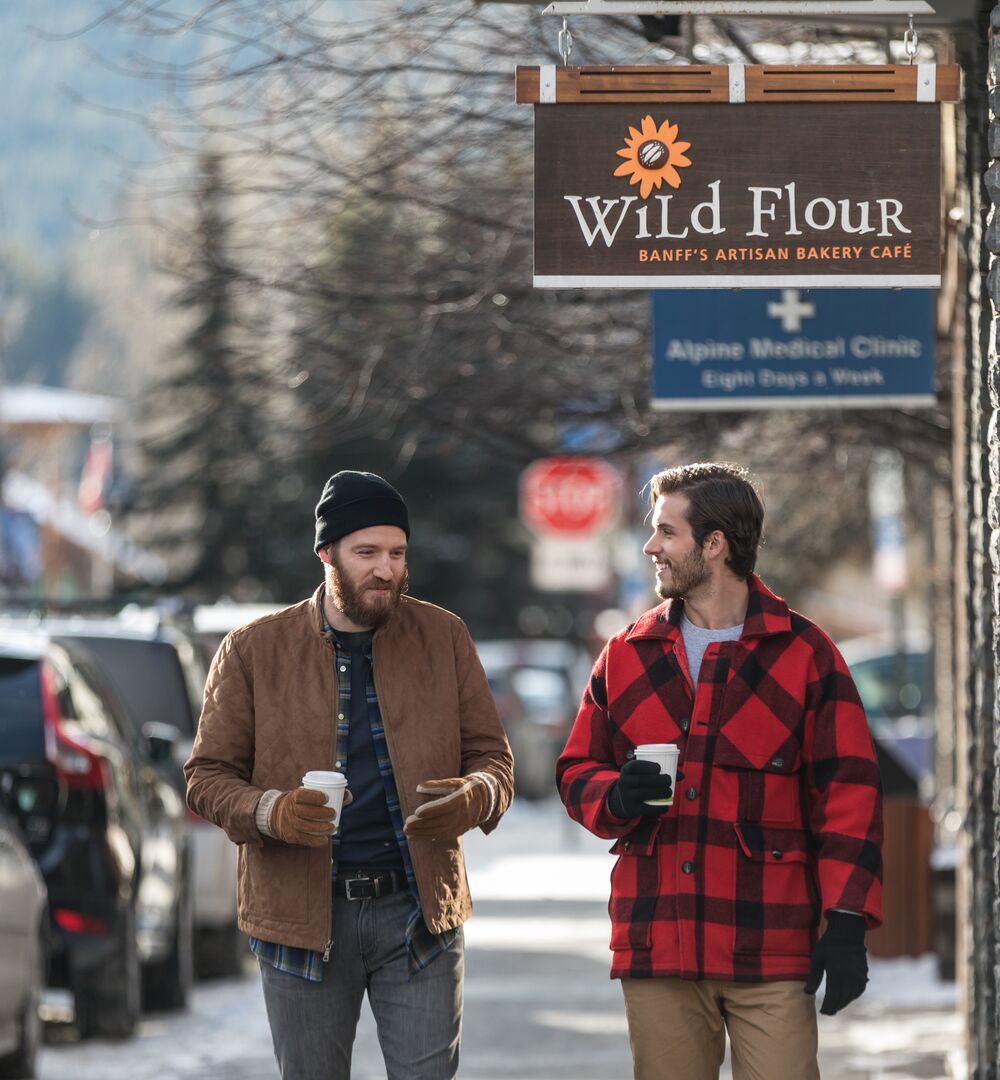 Two people walking down Bear Street with coffees in hand
